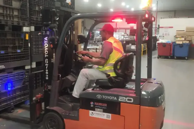 Operador em treinamento conduzindo empilhadeira em centro de distribuição