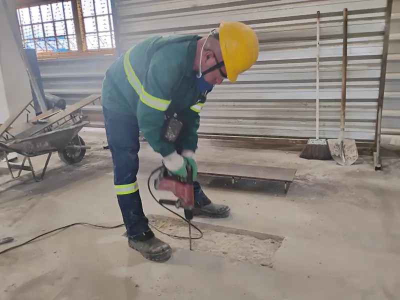 Trabalhador operando martelete com medidor de vibração e dosímetro durante avaliação de higiene ocupacional