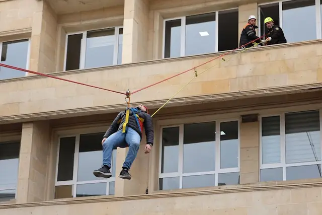 Simulação de resgate em trabalho em altura na fachada de um edifício durante treinamento prático